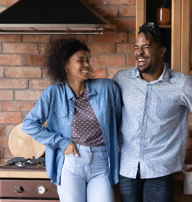 Young happy couple standing in their kitchen.