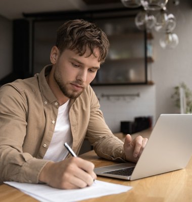 Young man calculating monthly payments using laptop.