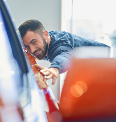 Young man admiring the finish of a new car.
