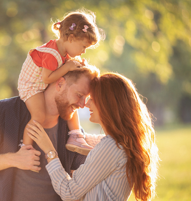 Young father and mother with their daughter outside on a sunny day.