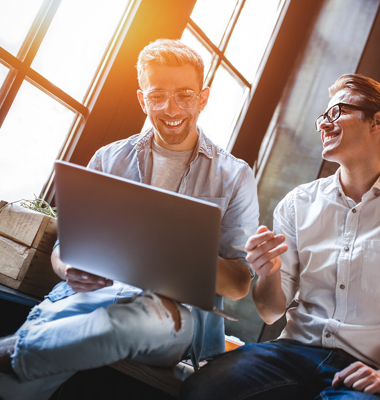 Two young male business looking at a laptop screen.