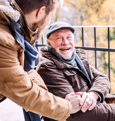 Elderly man in wheelchair being assisted by younger man.