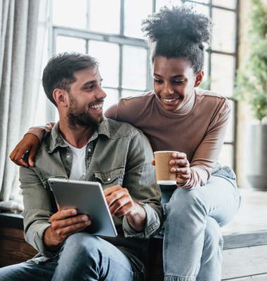 Young couple in stylish loft apartment reviewing payment info on a smart tablet.
