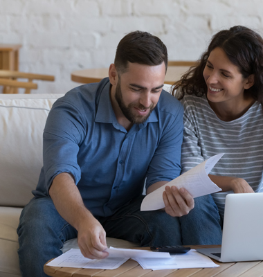 Young couple working on finances at living room table.