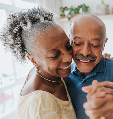 Older retired couple dancing in their kitchen.