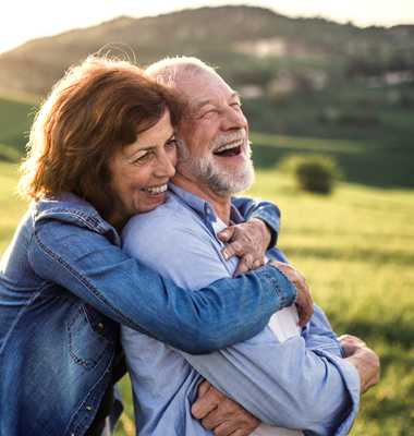 Older retired couple hugging and laughing.