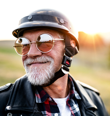 Older gentleman in motorcycle gear and sunglasses.
