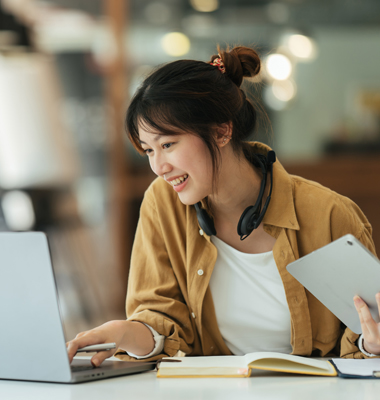 Young woman tracking expenses on laptop at home.