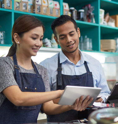 Young business owners in their shop going over finances on a smart tablet.