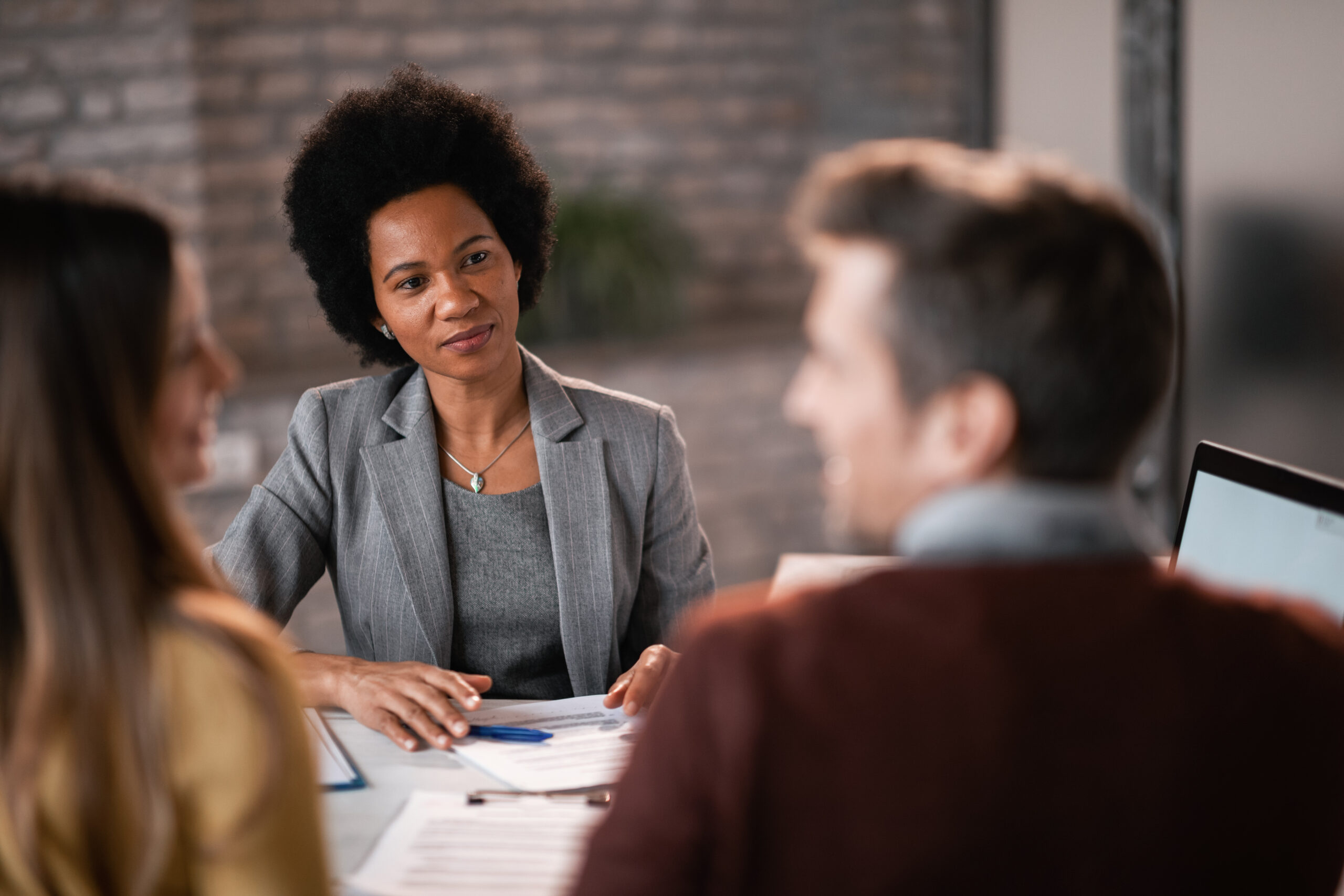 Smiling black real estate agent on a meeting with a couple.