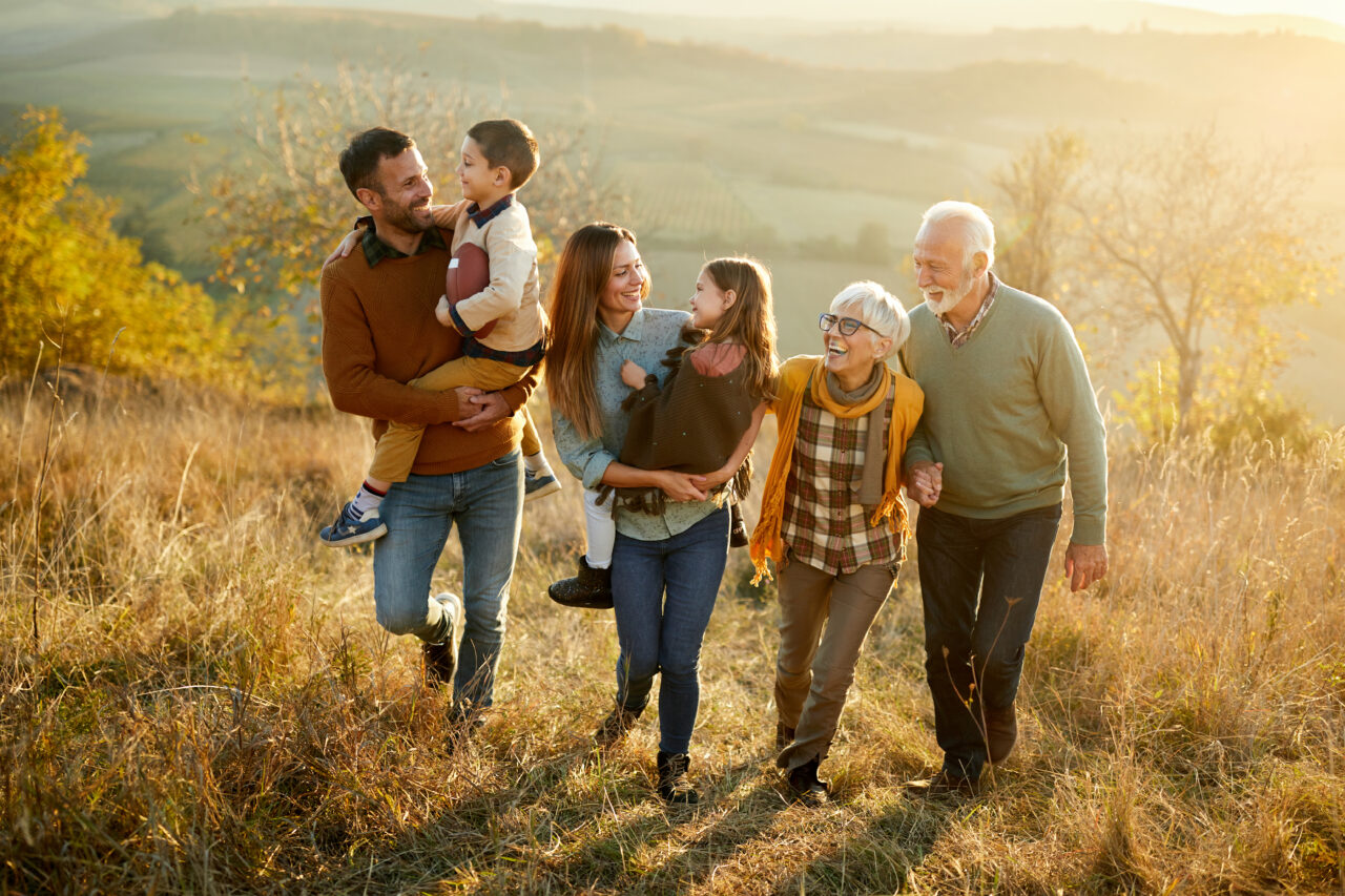 Happy multi-generation family talking while taking a walk on a hill.