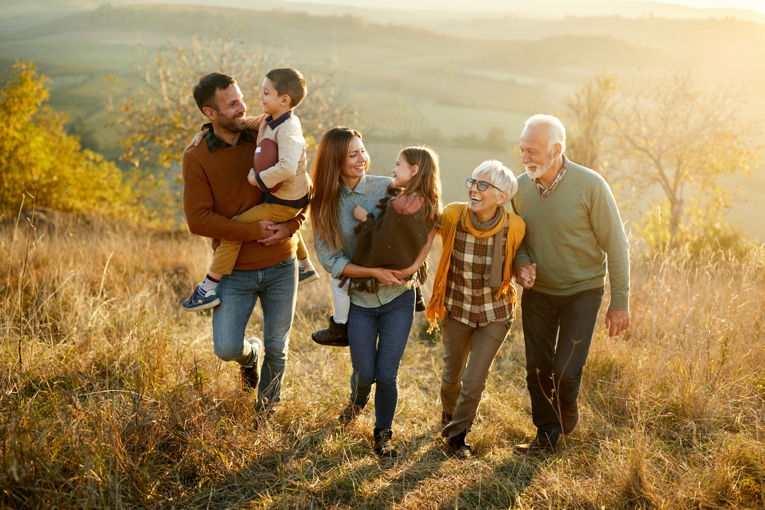 Happy multi-generation family talking while taking a walk on a hill.