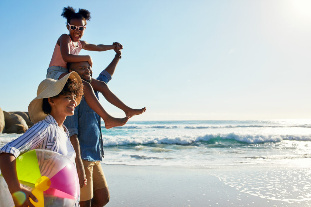 Shot of an adorable little girl going for a walk with her parents on the beach.