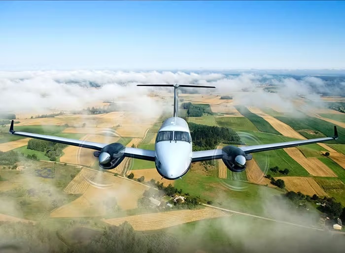 Twin prop airplane flying over countryside.