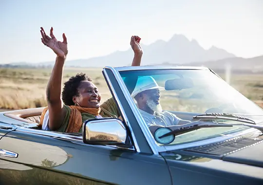 man and woman driving in a convertible