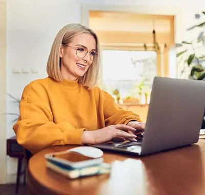 A woman in glasses typing on a laptop computer, focused on her work.