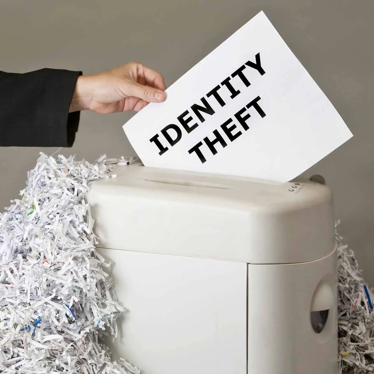 Hand inserting paper into a paper shredder to prevent identity theft