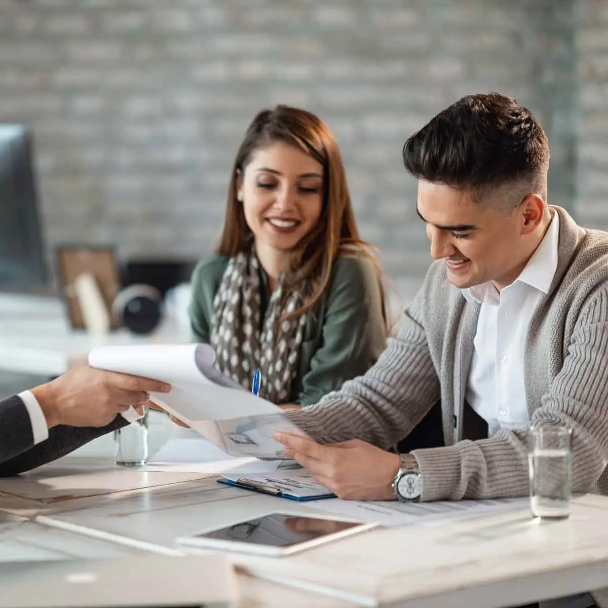 Three individuals seated at a table, deeply immersed in reviewing documents.