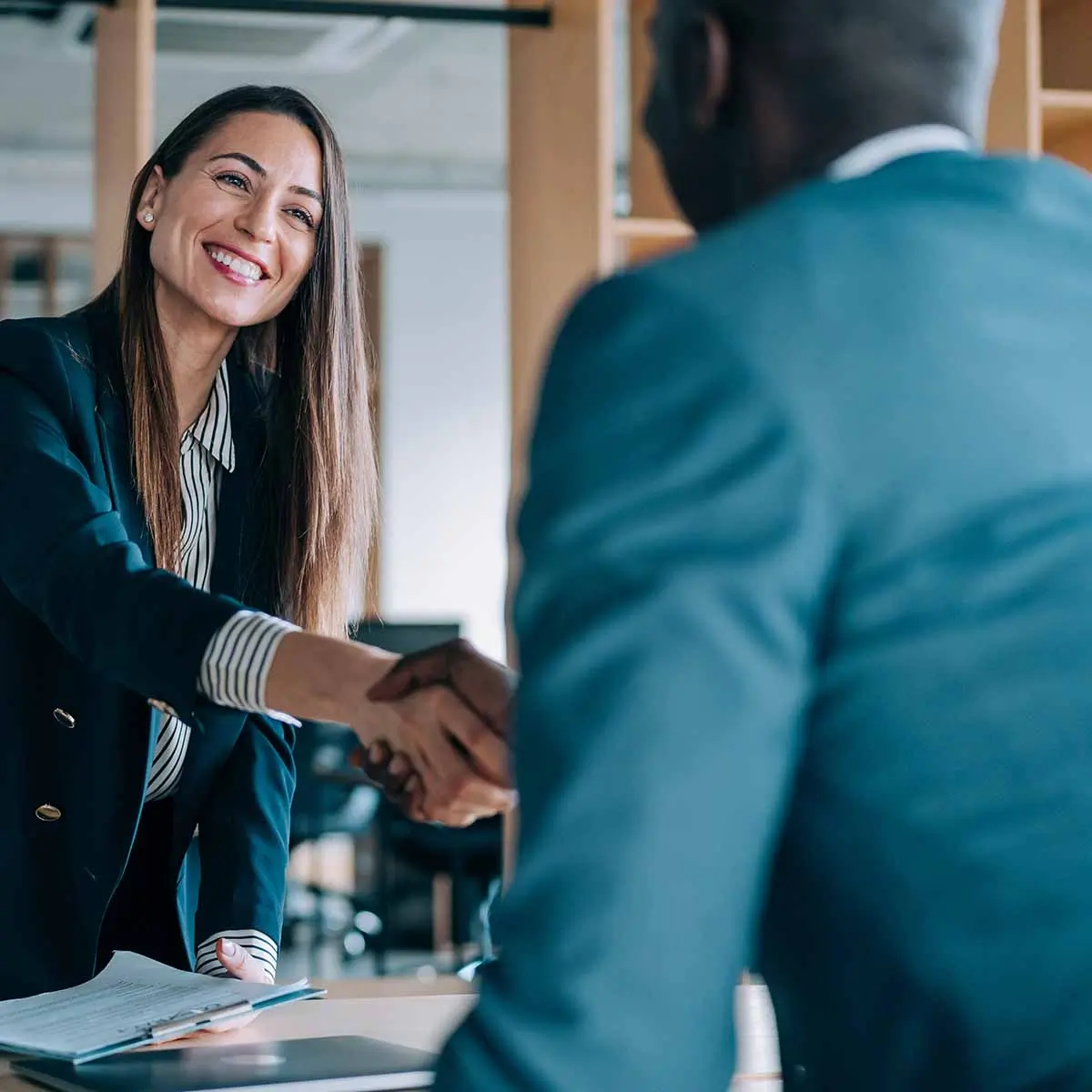 Professional woman and man shaking hands in office.