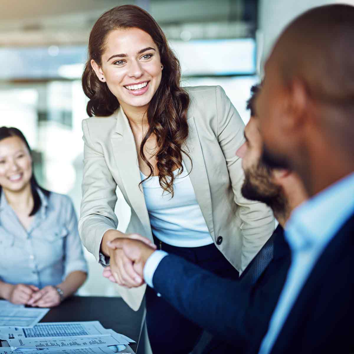 Professional woman and man shaking hands during a business meeting.