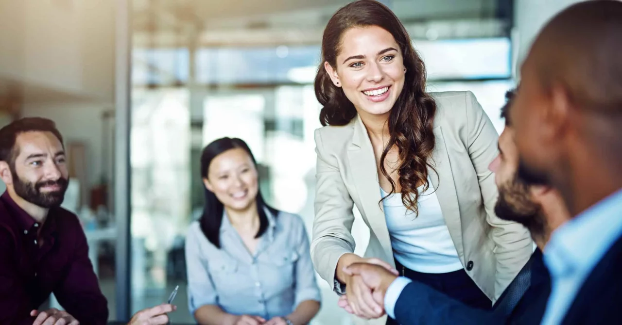 Professional woman and man shaking hands during a business meeting.