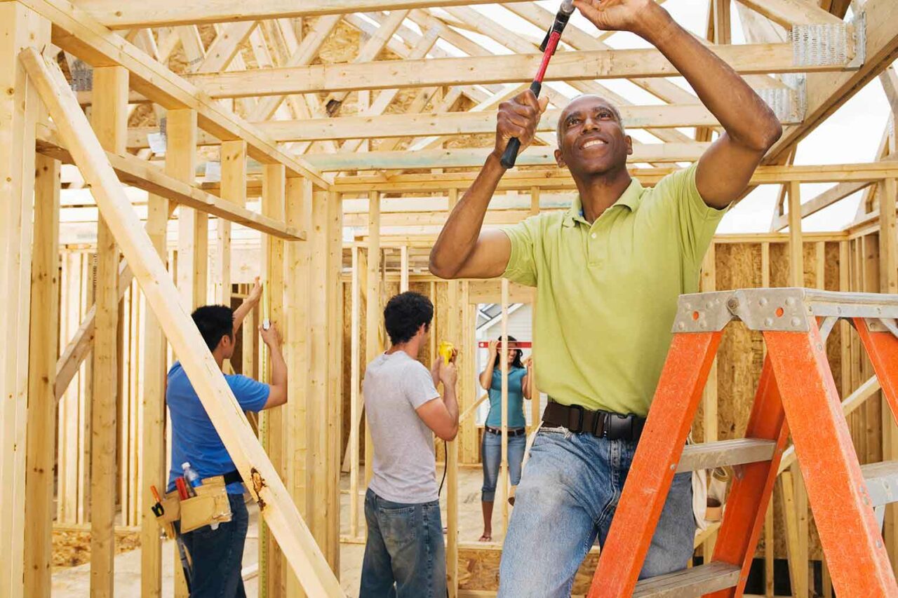 Volunteer hammering nail into wooden home construction