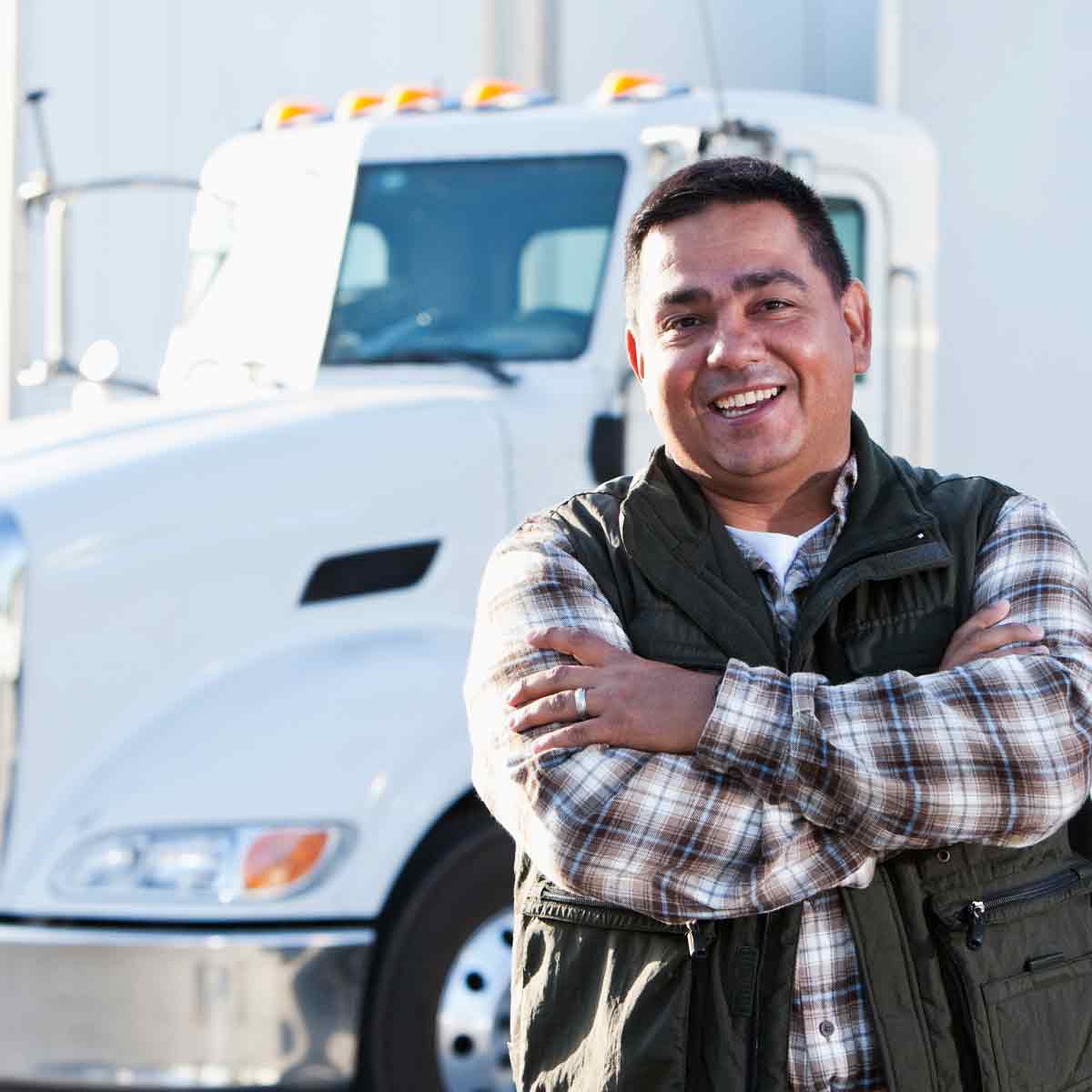 A man standing confidently in front of a semi truck.