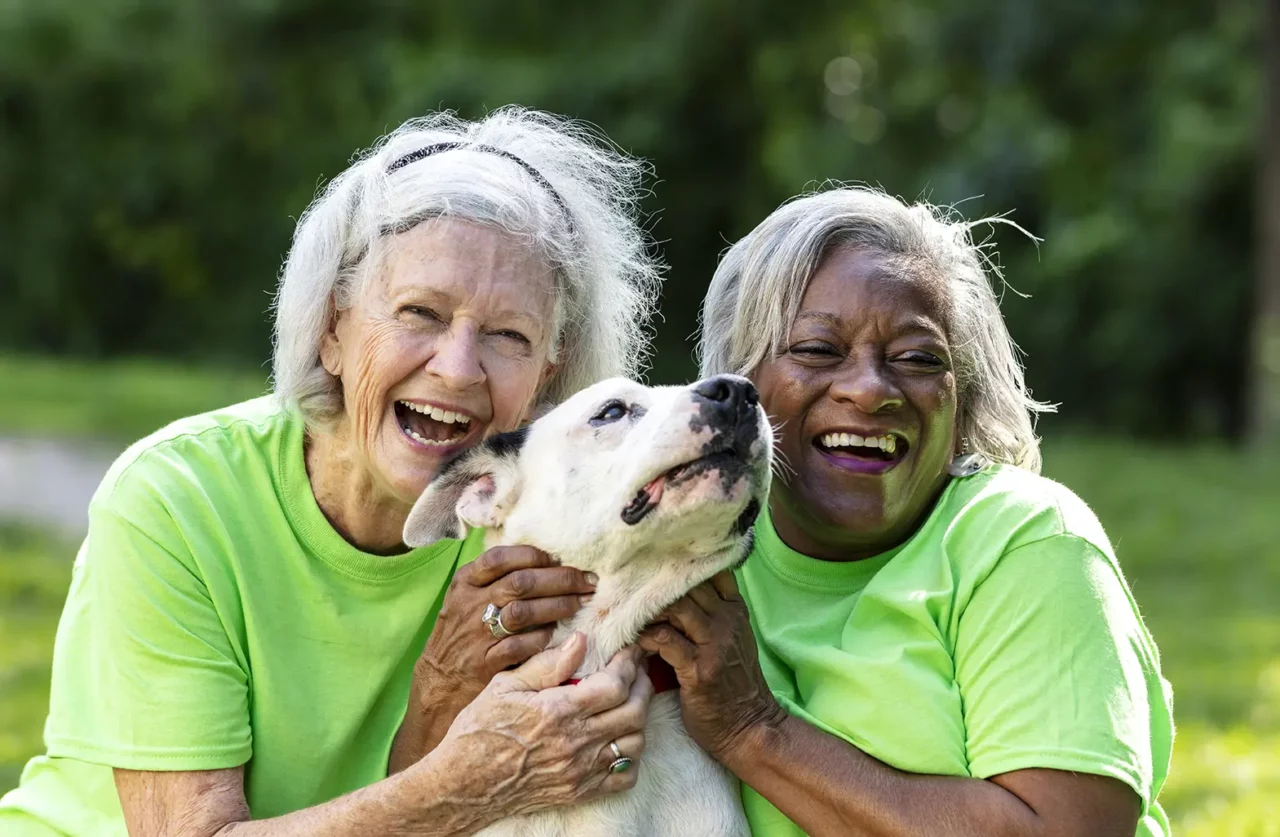 Two senior women volunteer at animal shelter, with dog