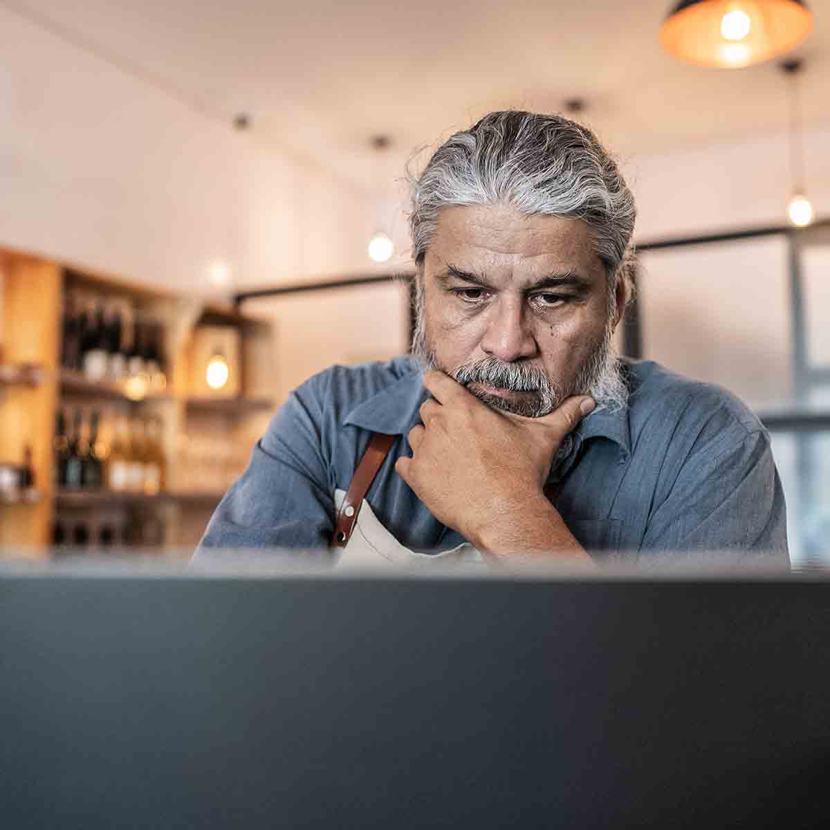 a man appears unsure as he gazes at his laptop screen with skepticism.