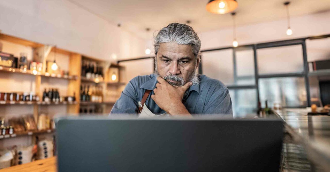 a man appears unsure as he gazes at his laptop screen with skepticism.