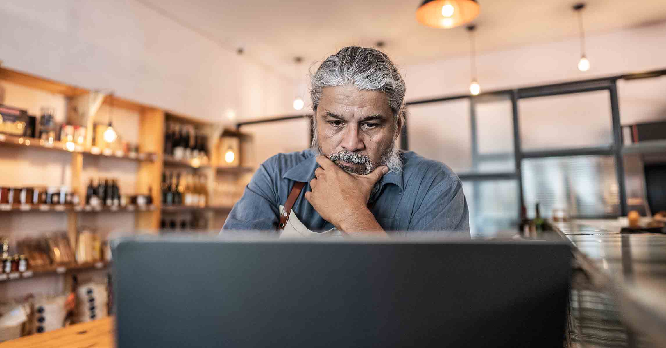 a man appears unsure as he gazes at his laptop screen with skepticism.