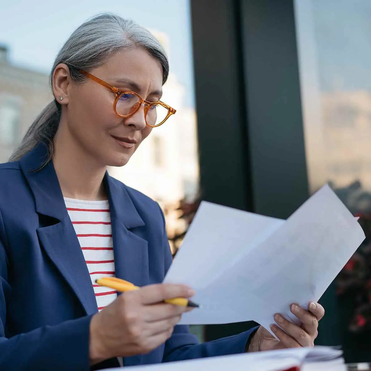 Woman with glasses reviewing paperwork.