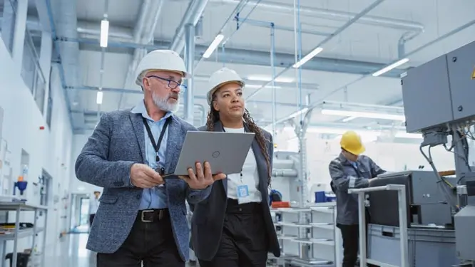 Two diverse manufacturing engineers observing the factory floor and talking