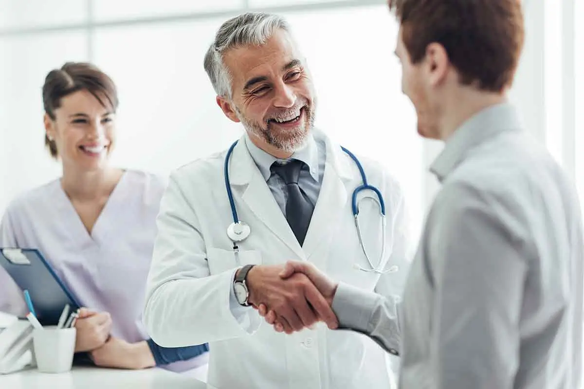 A doctor and a young man shake hands, symbolizing trust and collaboration