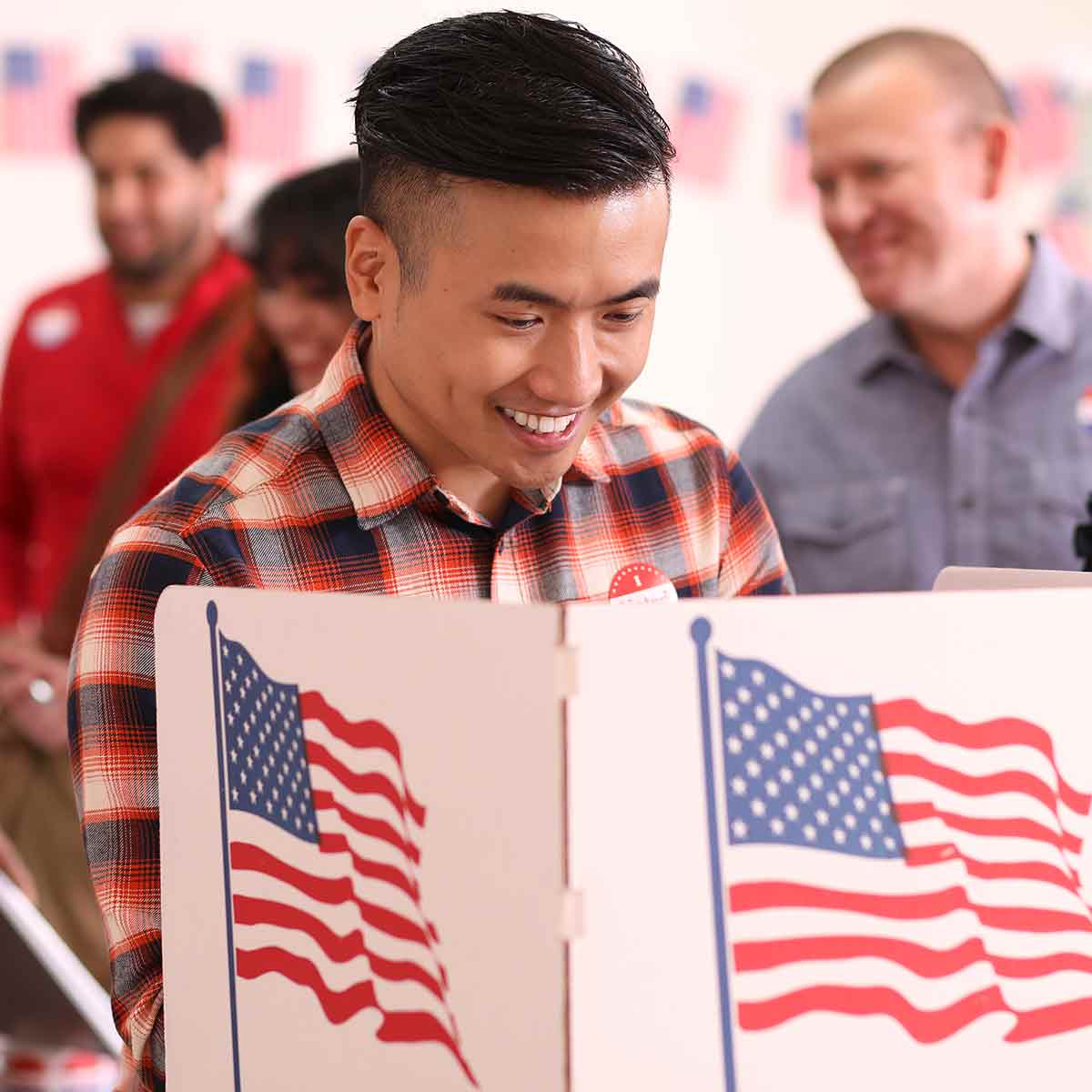 A smiling man stands in a voting booth, proudly participating in the election and exercising his right to vote.