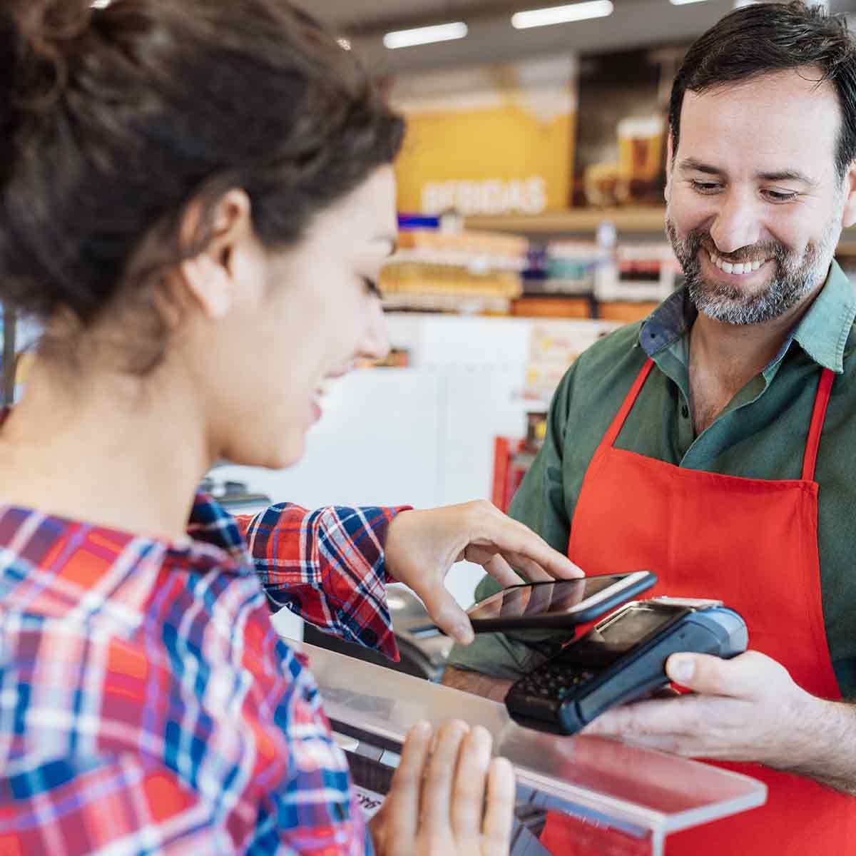 Woman using her phone for a contactless payment at checkout with a digital wallet