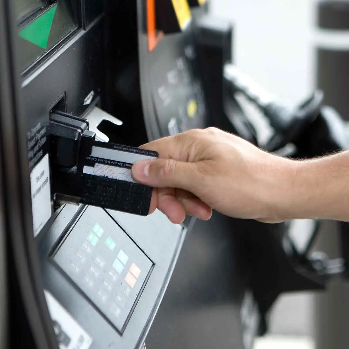 Swiping a debit card at a gas pump with a potential credit card skimmer scam.