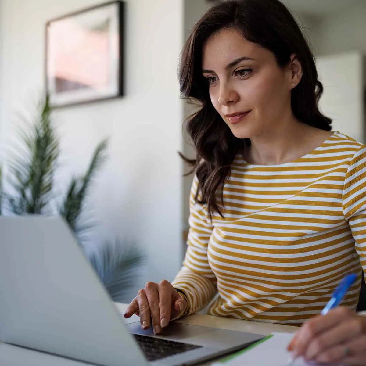 A woman working on her laptop, reviewing financial documents