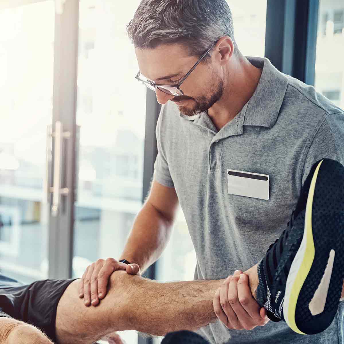 Physical therapist assisting a patient with leg rehabilitation exercises.