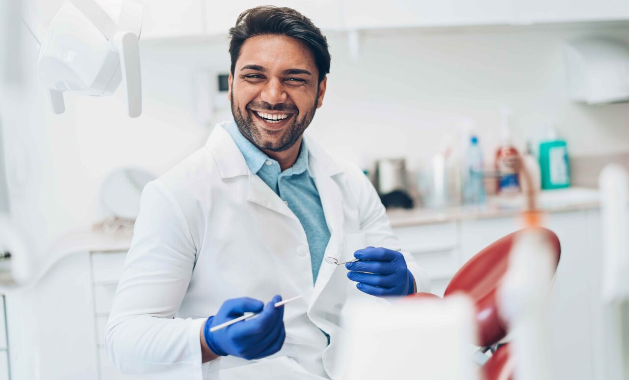 Dentist looking up from dental work and smiling, conveying a friendly and professional environment for patient care in his Indiana dental office