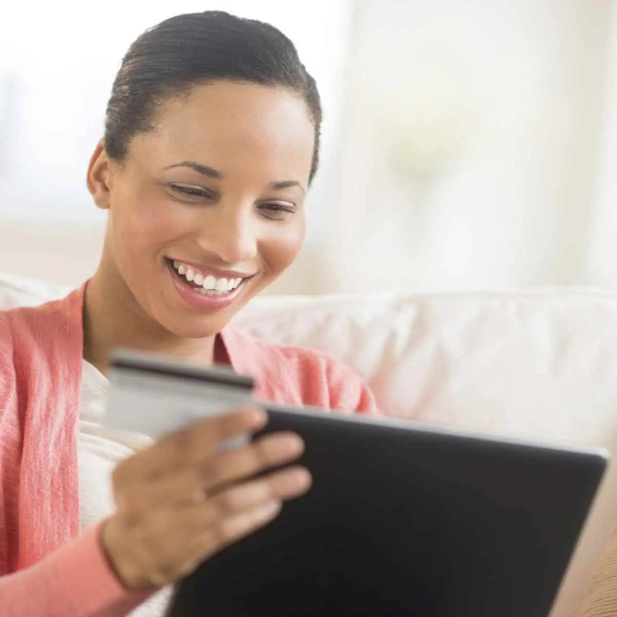 Smiling woman entering her credit card number to make an online purchase on Black Friday