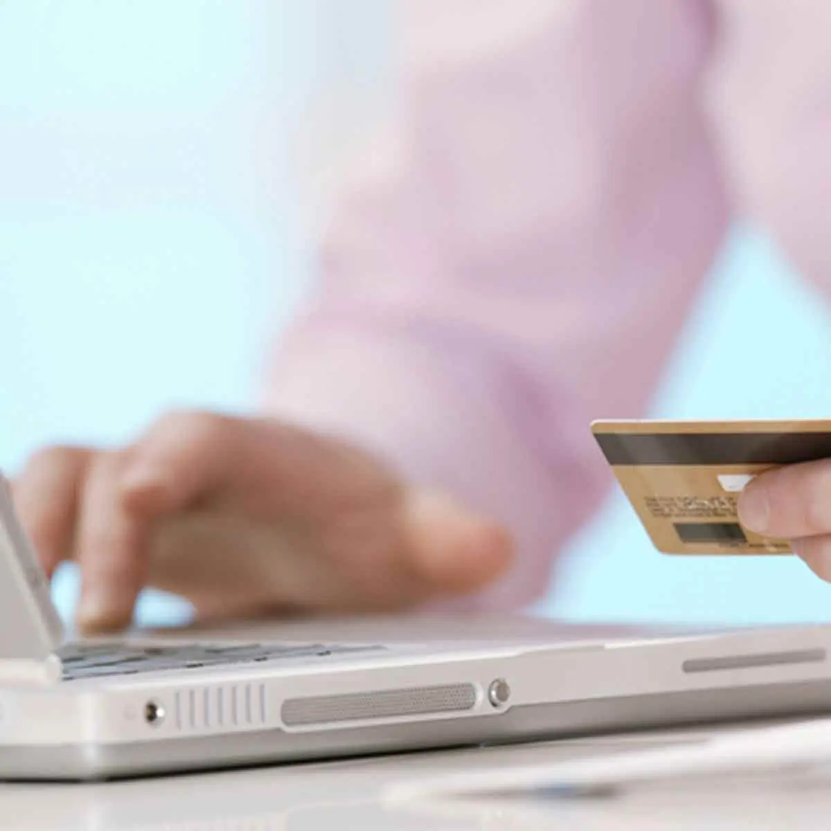 Hand entering a credit card number on laptop to illustrate safe online shopping and ID theft scams