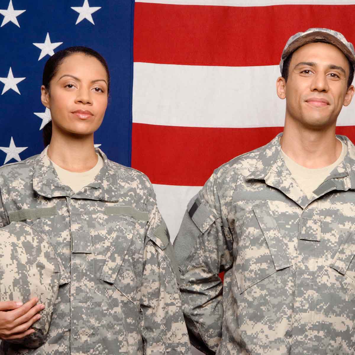 Two soldiers, a man and a woman, standing in front of an American flag, representing VA loan benefits for veterans and service members.