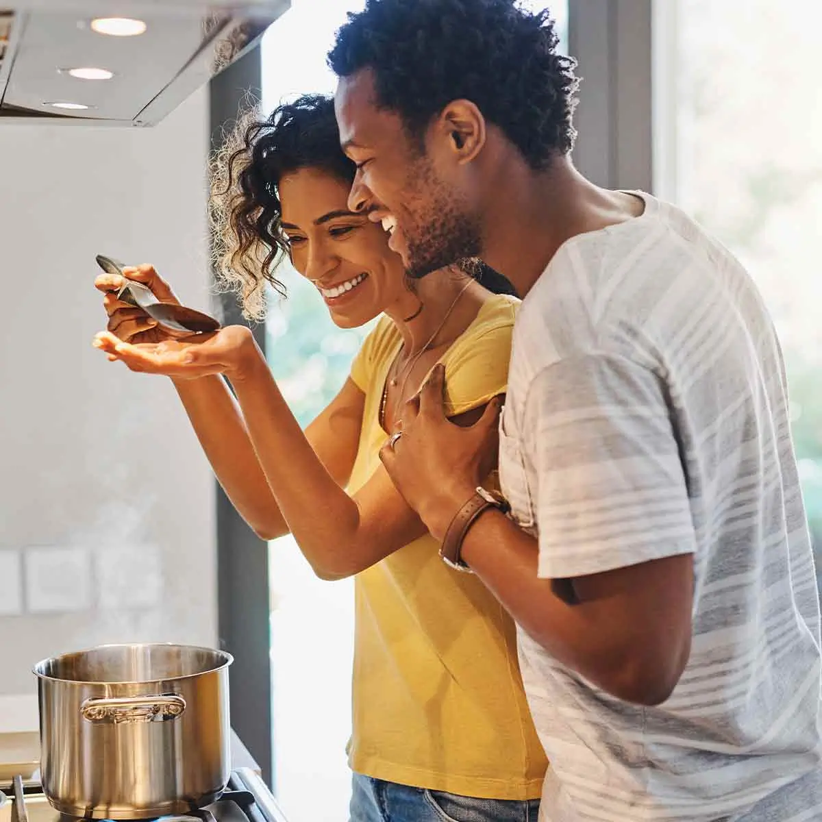 Carefree couple cooking and laughing in their kitchen, enjoying the fruits of wise budgeting and financial planning