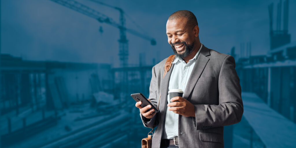 A professional man in a suit looks at his phone, coffee in hand, managing the online deposits for his business