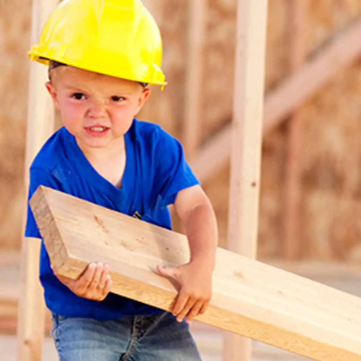 Toddler wearing a hard hat lifting a piece of lumber, representing how you can add on to your home with a HELOC