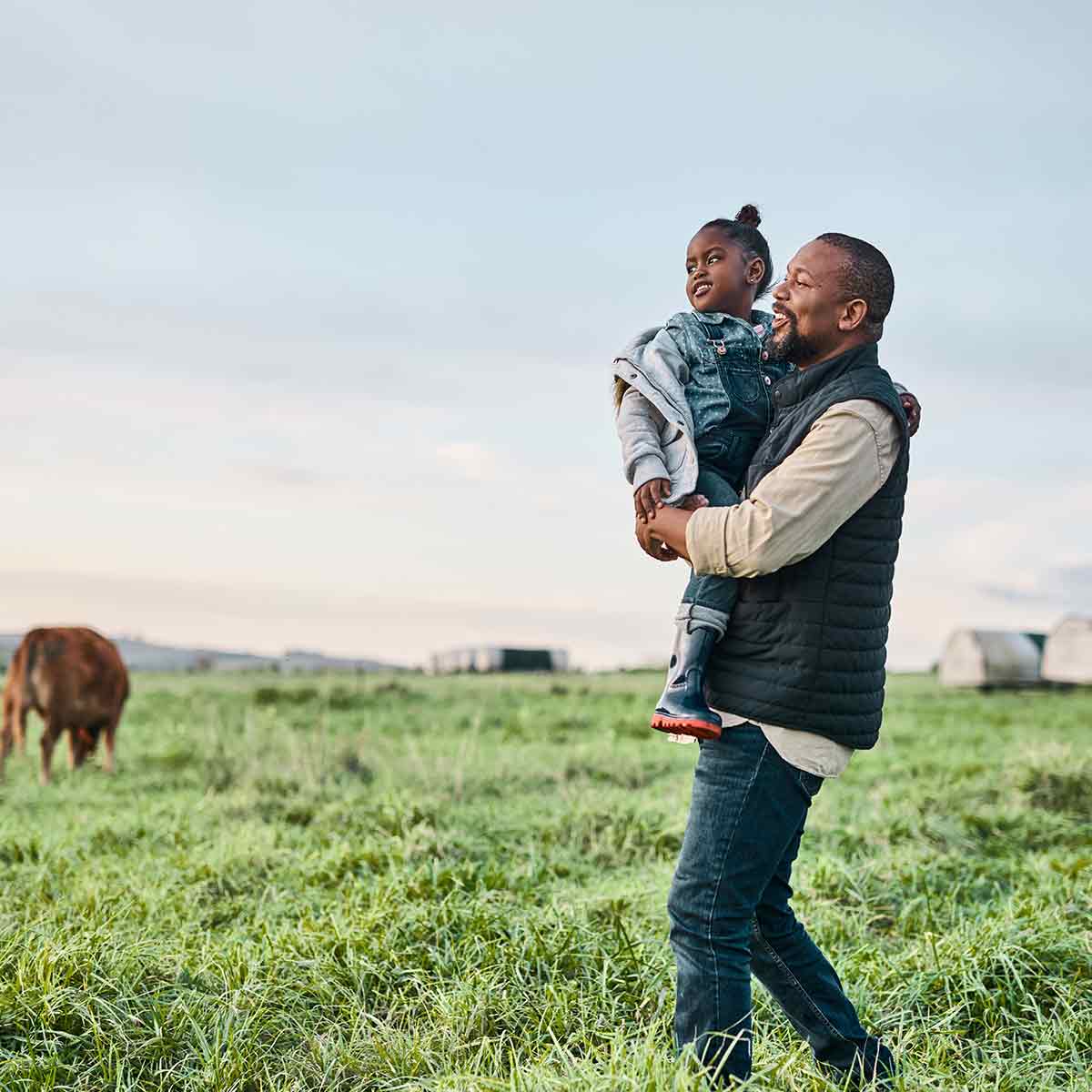 Rancher and toddler on farm, showcasing the future of farming with USDA loan support.