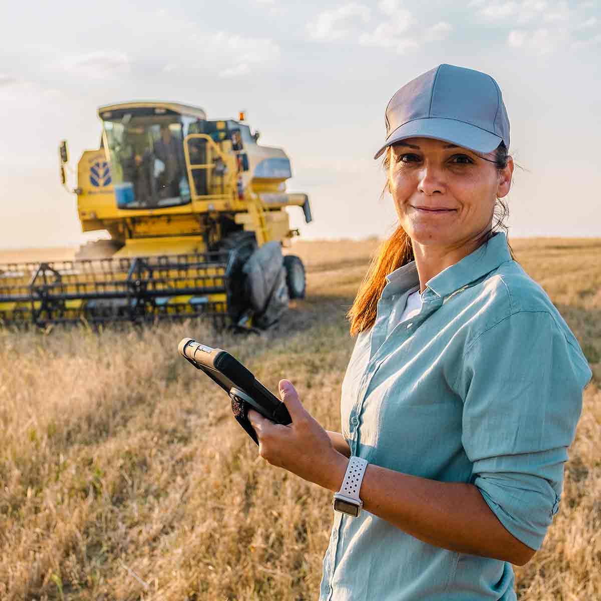 Female farmer using tablet in field, managing her agricultural business funded by USDA loans.