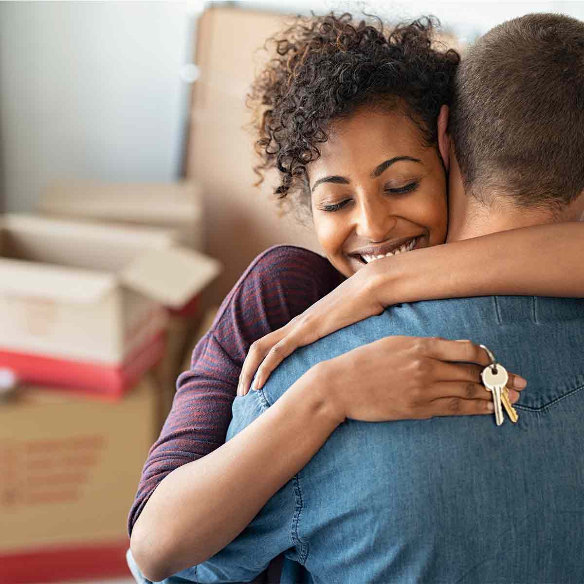 First-time homebuyers hugging as they move into in their new house