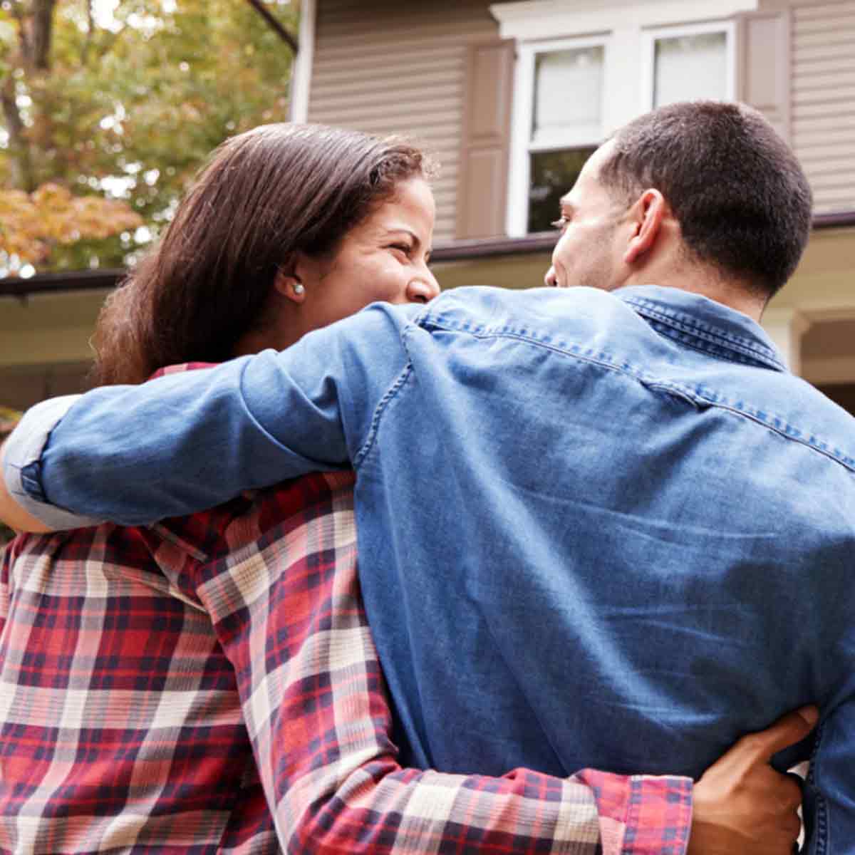 Happy couple embracing in front of their new home